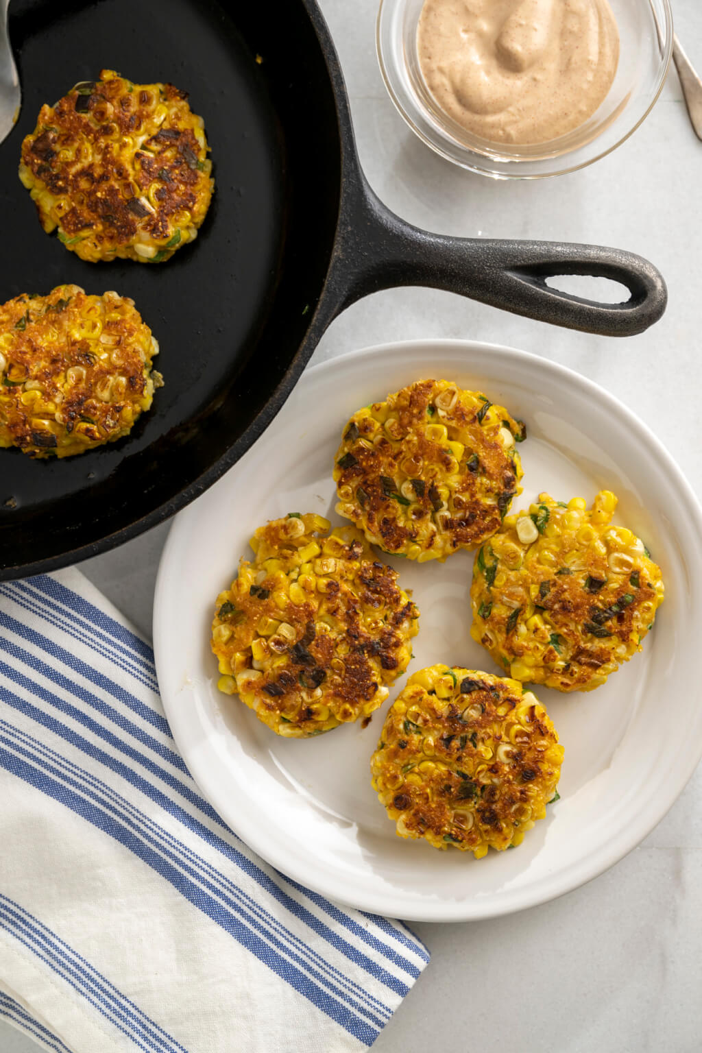 Golden corn fritters are a deliciously easy way to repurpose leftover corn and there's no need to deep fry. The simple sauce is optional but takes the fritters to the next level. Entertaining? Make appetizer-size fritters!
