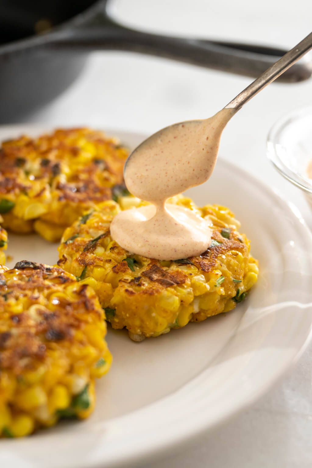 Golden corn fritters are a deliciously easy way to repurpose leftover corn and there's no need to deep fry. The simple sauce is optional but takes the fritters to the next level. Entertaining? Make appetizer-size fritters!